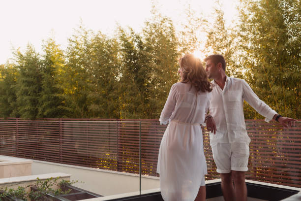 A couple dressed in white on a terrace at sunset