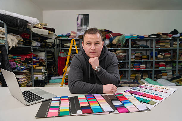 A man at a table with colour swatches and a laptop in a fabric store