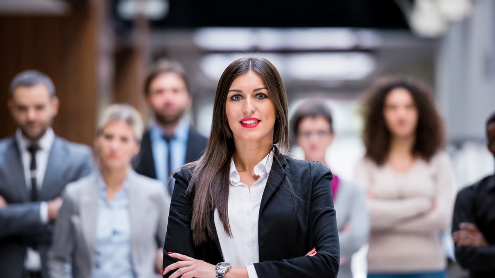 A smiling businesswoman in front of a group of colleagues