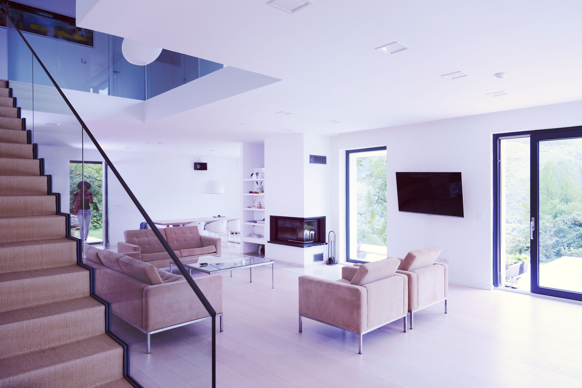 A bright white living room with a staircase and a fireplace
