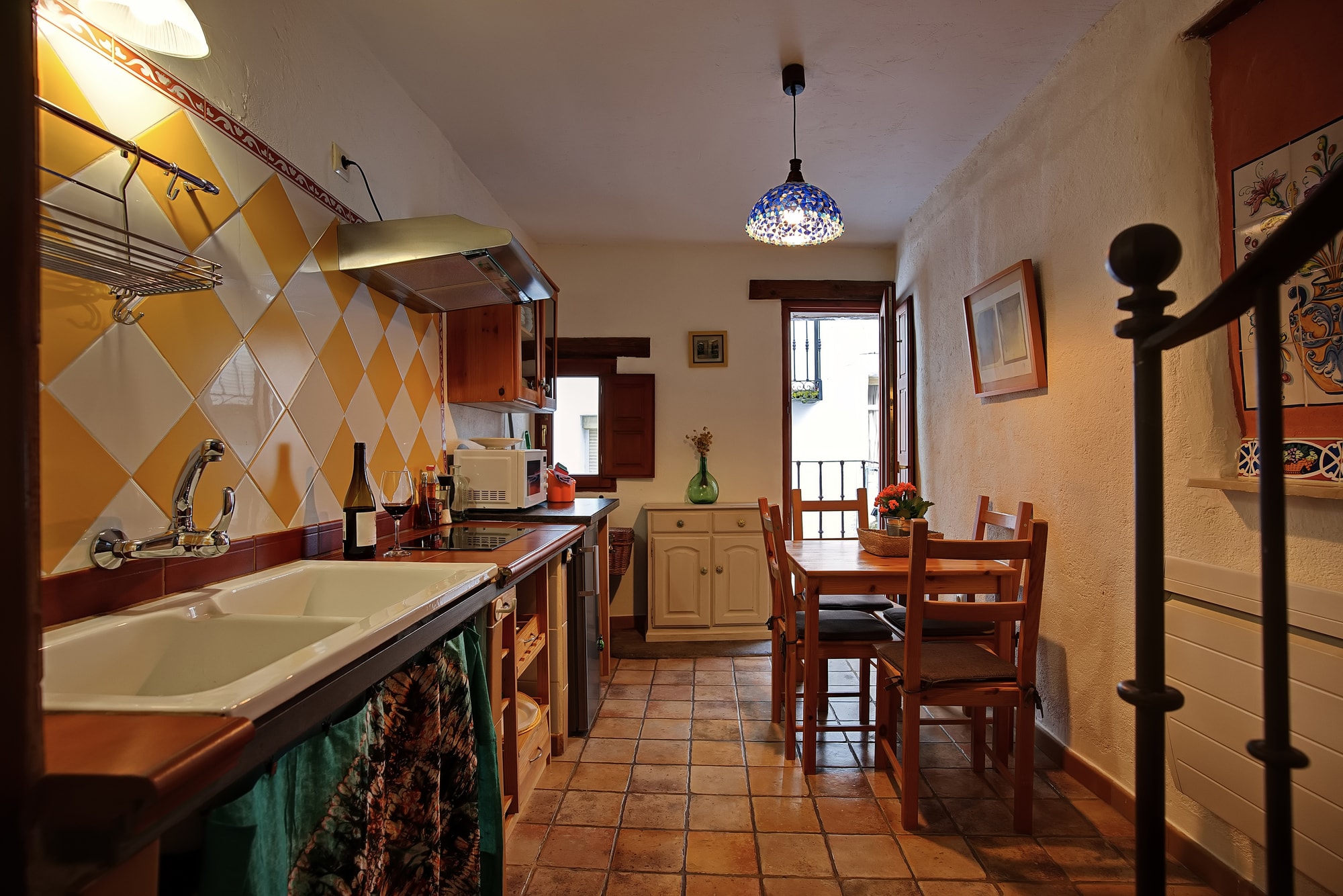 A rustic kitchen and dining area with a tiled floor and a staircase